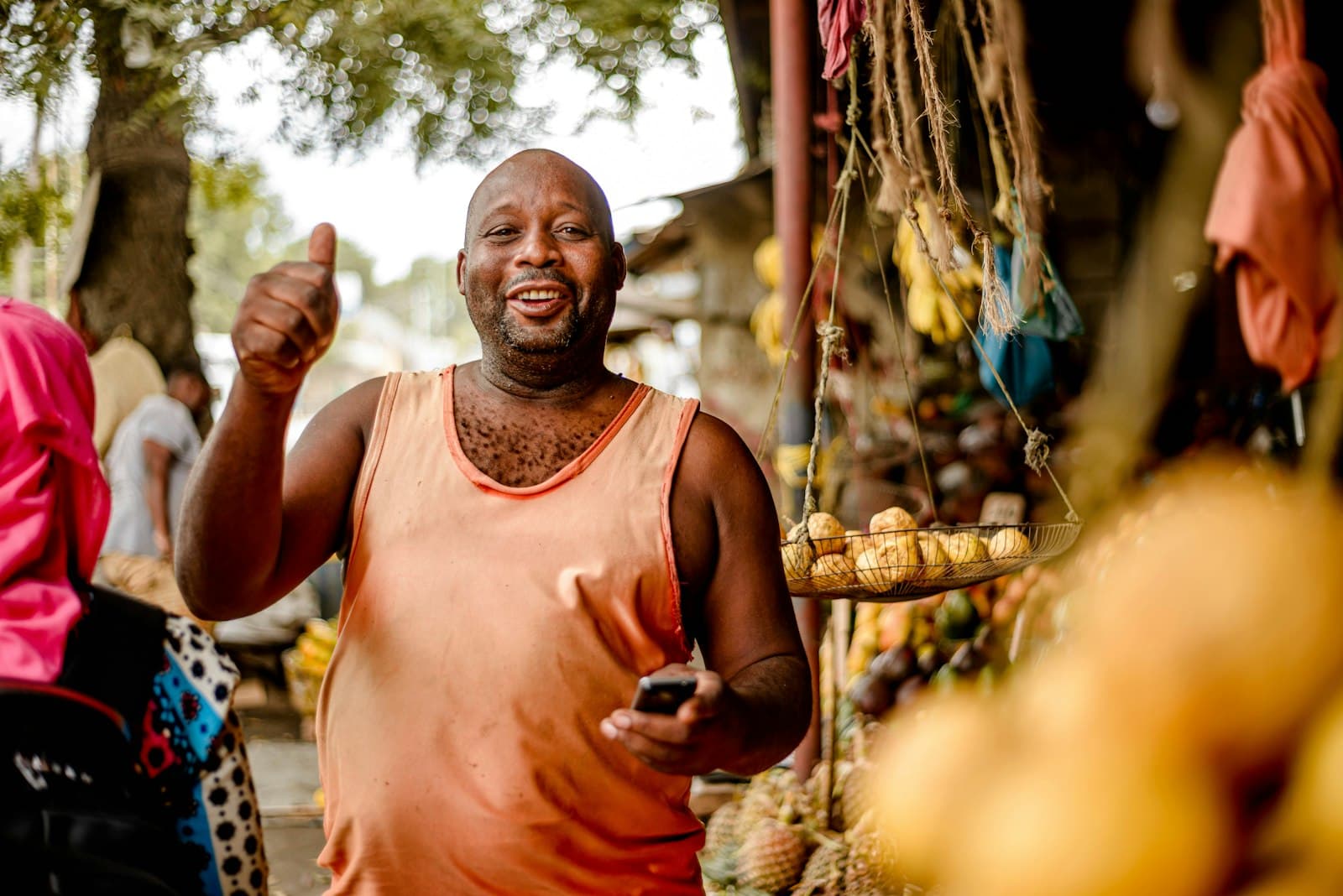 A smiling produce trader with his phone at his market stall